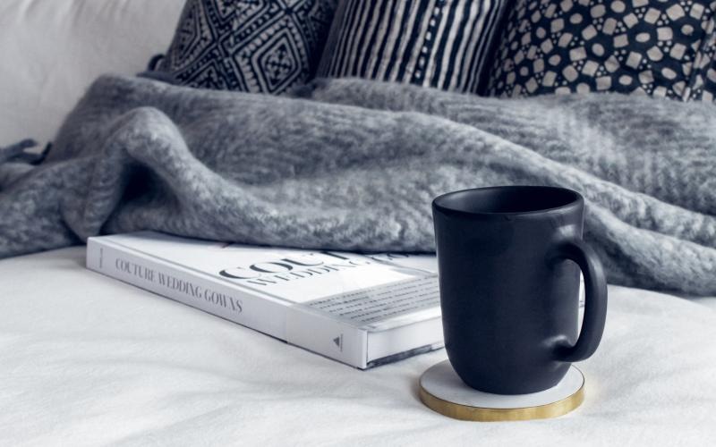 a book and a mug on a bed